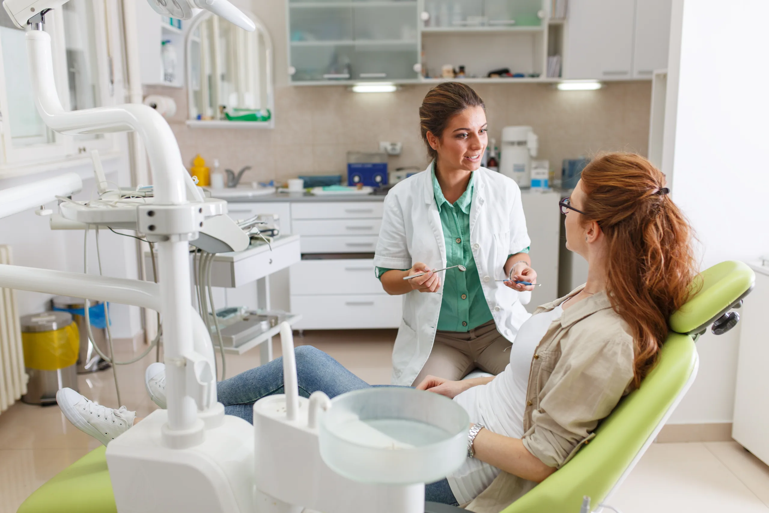 A dentist talking with a patient sitting in the chair