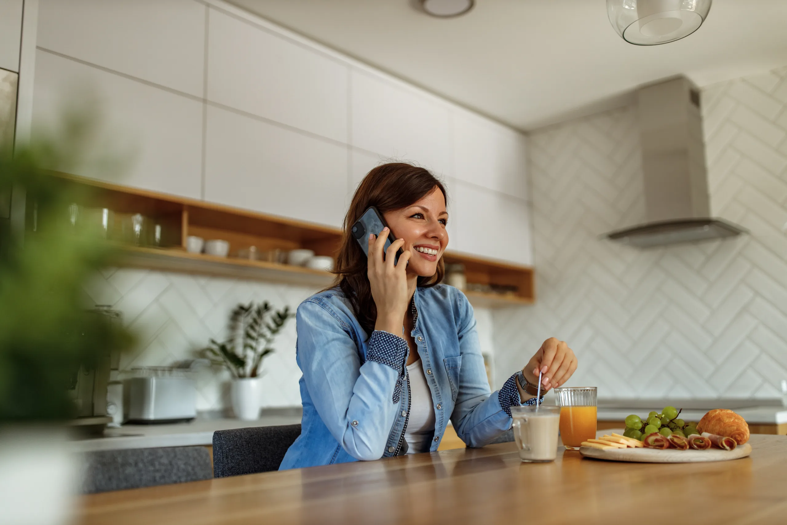 A woman sitting at her kitchen table, talking on the phone